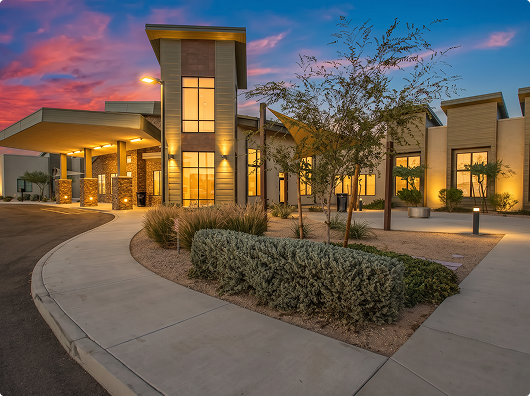 Evening exterior facade with illuminated entrance and curved driveway