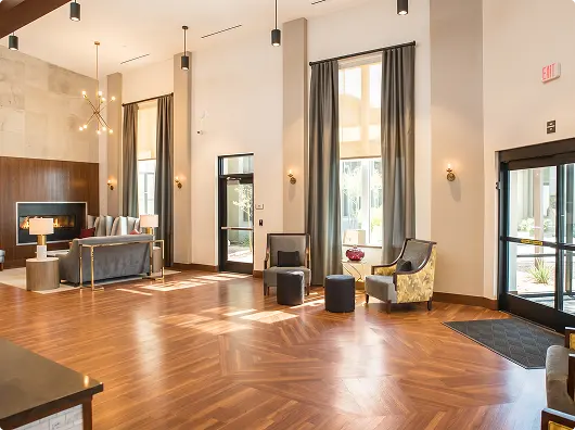 Sunlit common hall with lounge furniture and tall windows